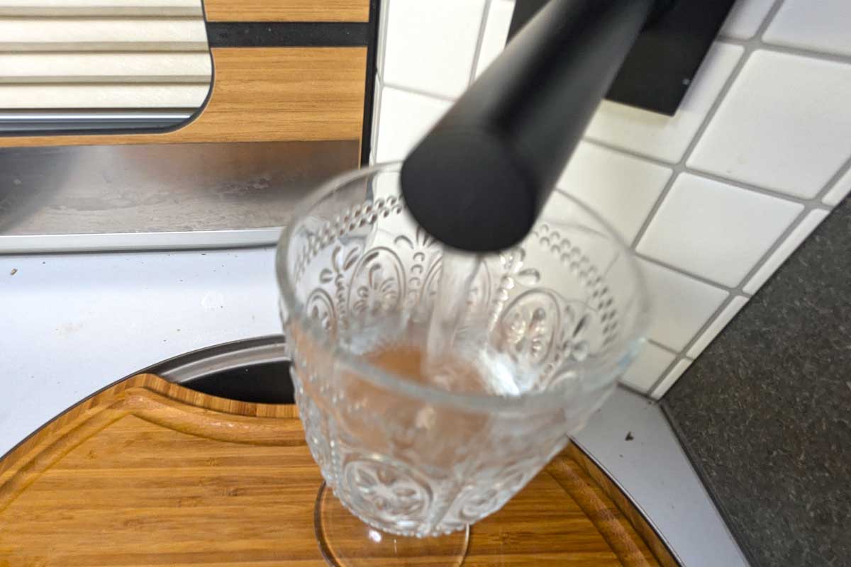 Glas wird am Wasserhahn gefüllt