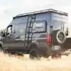 Schwarzer Mercedes Sprinter 4x4 Campervan mit Dachträger, Leiter und Reserverad im offenen Gelände
