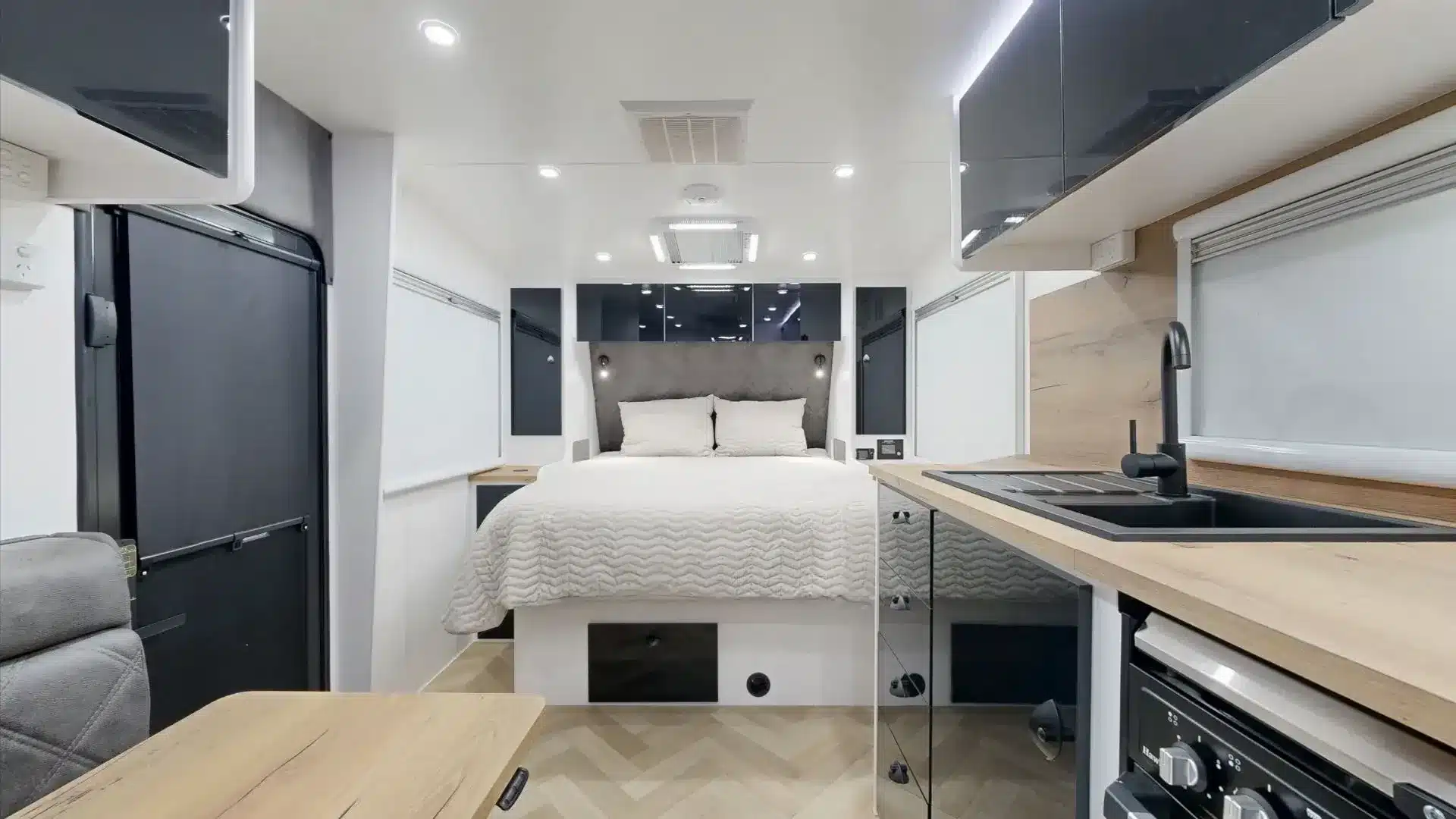 Innenansicht des 2025 Cadillac RV 216 Gaia mit Queen-Bett, Küchenzeile und modernen Einbauten