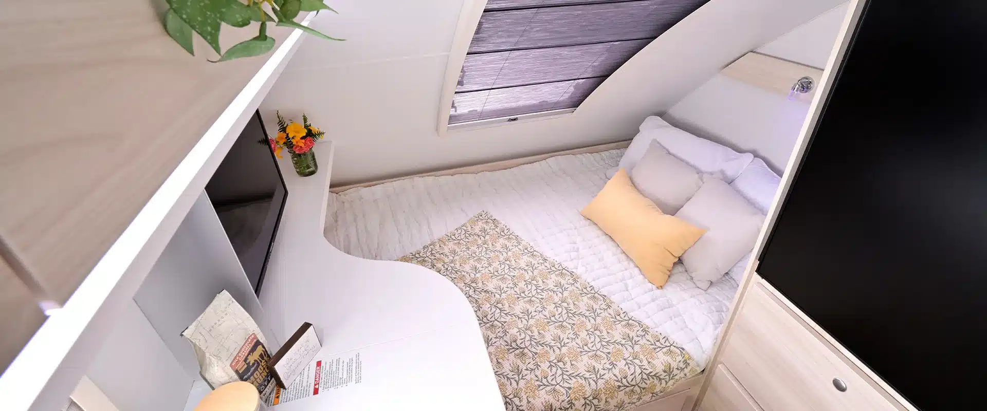 Innenansicht des Schlafbereichs im TAB 400 Teardrop Camper mit Bett, Kissen, Decke, Fenster und Stauraum