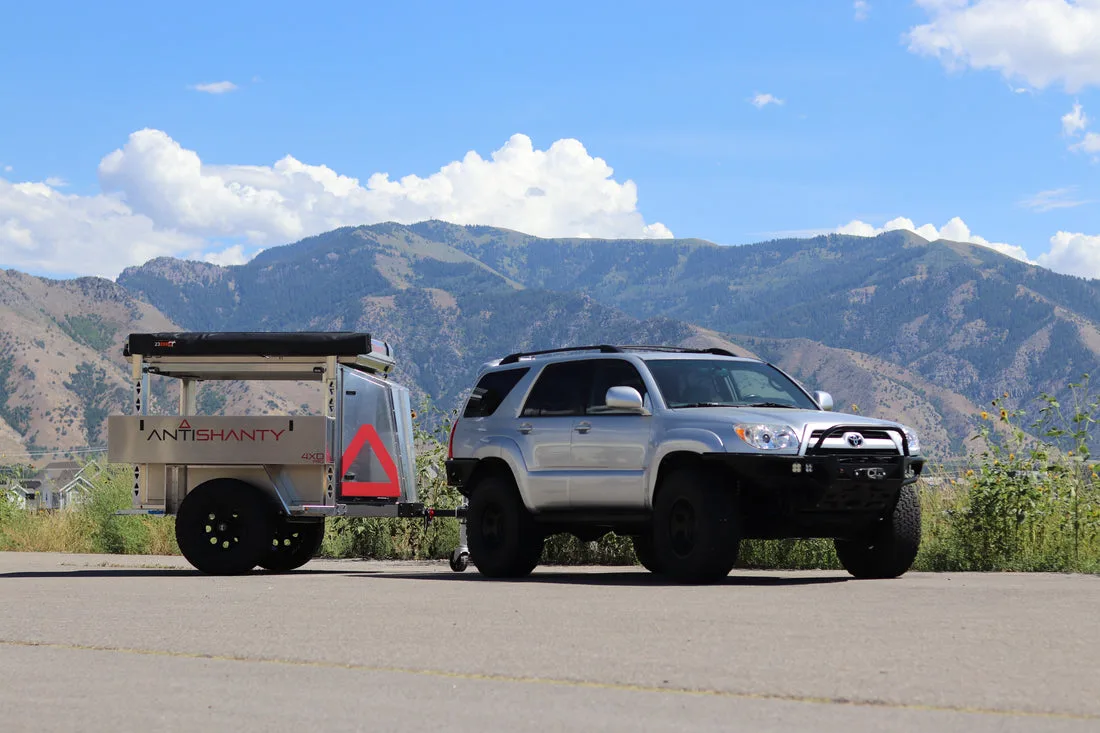 Antishanty 4XD Offroad-Trailer aus Aluminium, angehängt an einem SUV, vor einer Berglandschaft