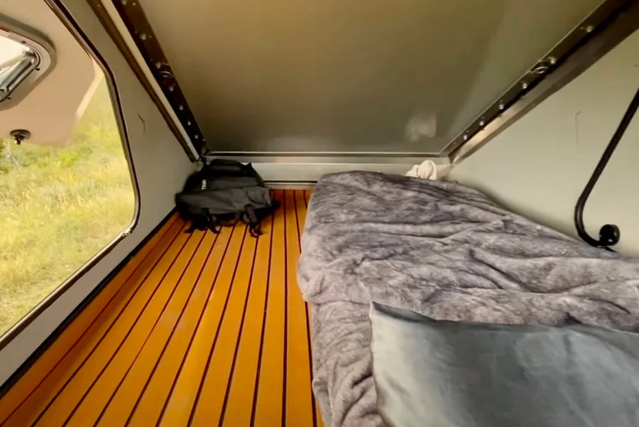 Blick in den Innenraum eines 4XD Offroad-Trailers mit Matratze und Fenster, Holzboden und isolierten Wänden