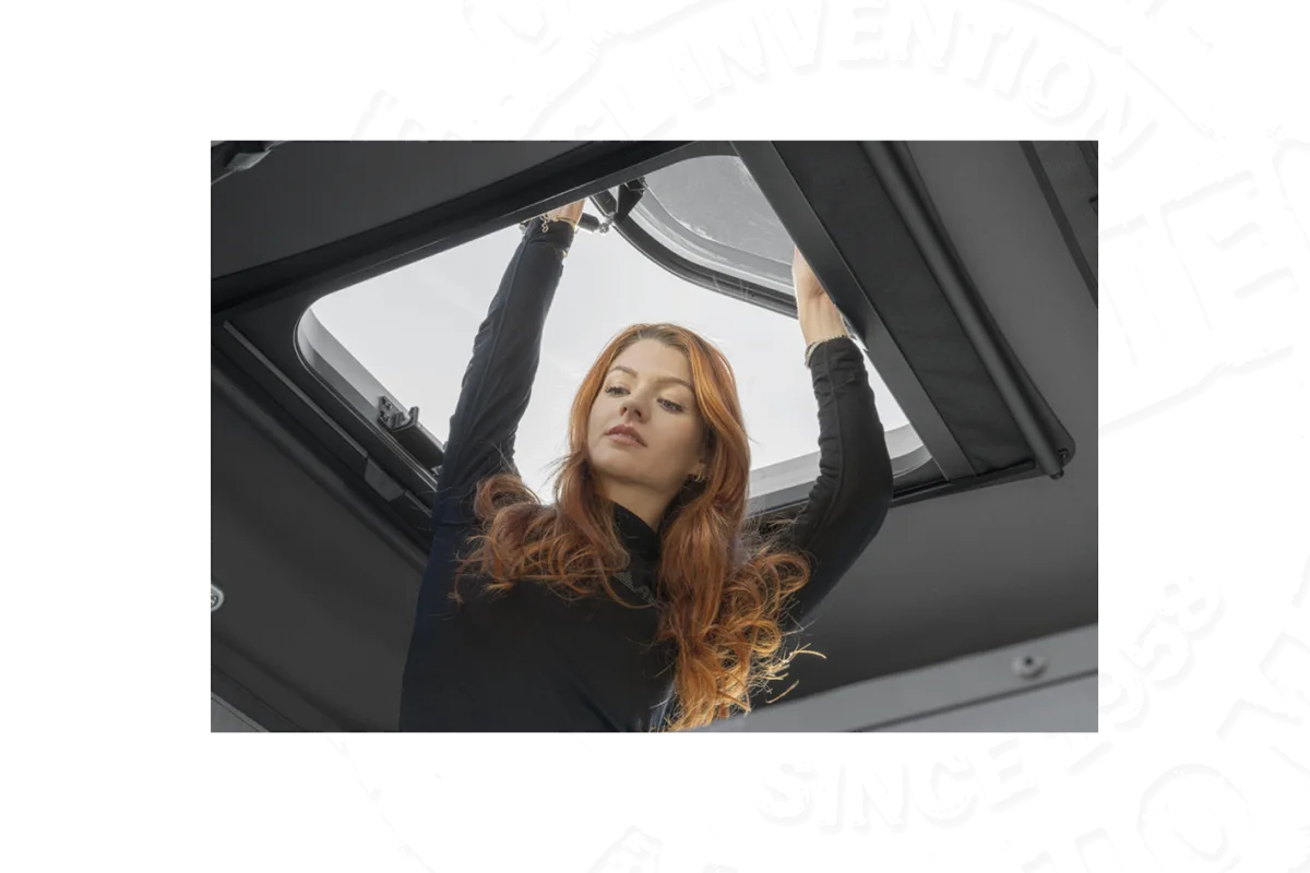 Frau öffnet das Panoramafenster eines Hartschalen-Dachzelts von innen