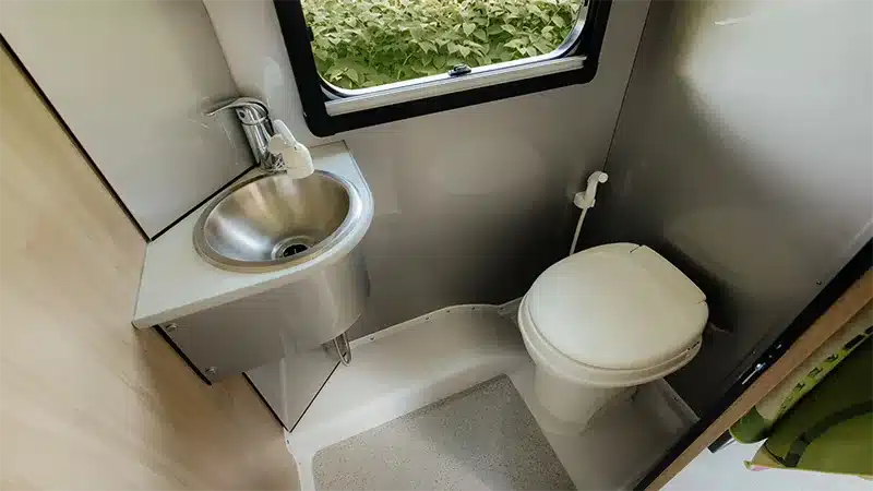 Blick in das Badezimmer des Alto F1743 Expedition mit Spültoilette, Edelstahl-Waschbecken und Fenster