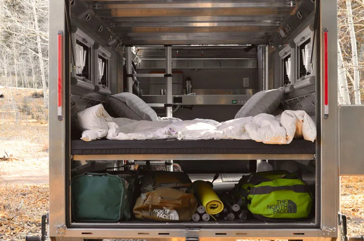 Innenansicht des AntiShanty AS-1 A-Frame Trailers mit aufgebautem Bett und darunterliegendem Stauraum für Ausrüstung