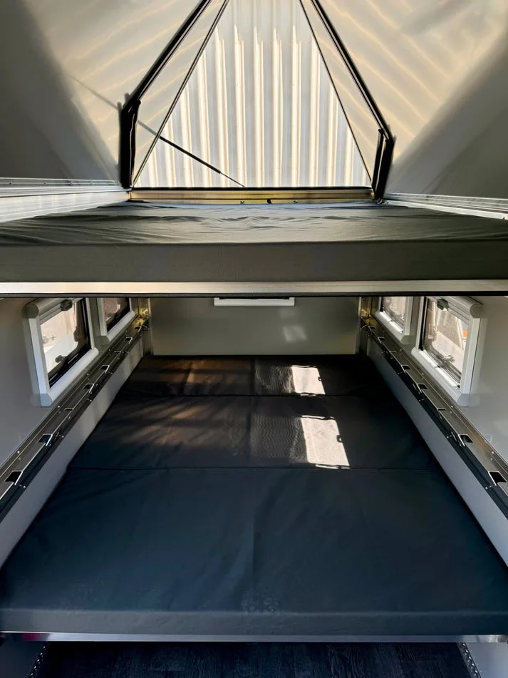 Blick in den Innenraum des AntiShanty AS-1 A-Frame Trailers mit zwei übereinander angeordneten Queen-Size-Betten und großen Fenstern