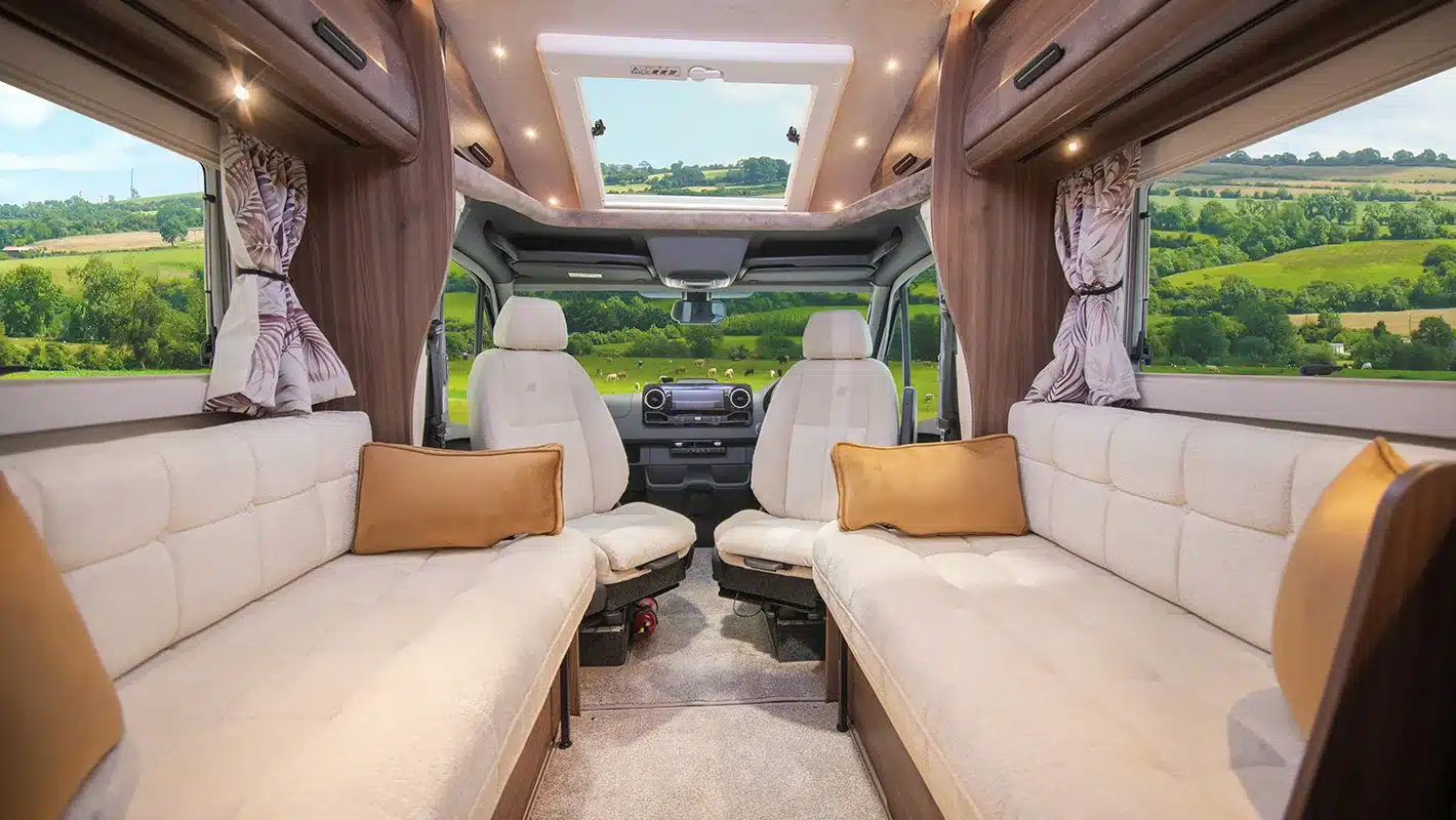 Innenansicht des Auto-Sleepers Burford Duo Wohnmobils mit zwei Sofas, Fahrerhaussitzen und großem Panoramadach