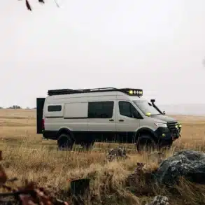 AWOL Sprinter Iglhaut Allrad 170 auf einer Wiese im Gelände, ausgestattet mit Dachträger, Zusatzscheinwerfern und Offroad-Bereifung