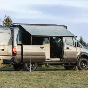 Benchmark Apprentice Campervan auf Mercedes Sprinter 144 AWD Basis mit ausgefahrener Markise auf einer Wiese