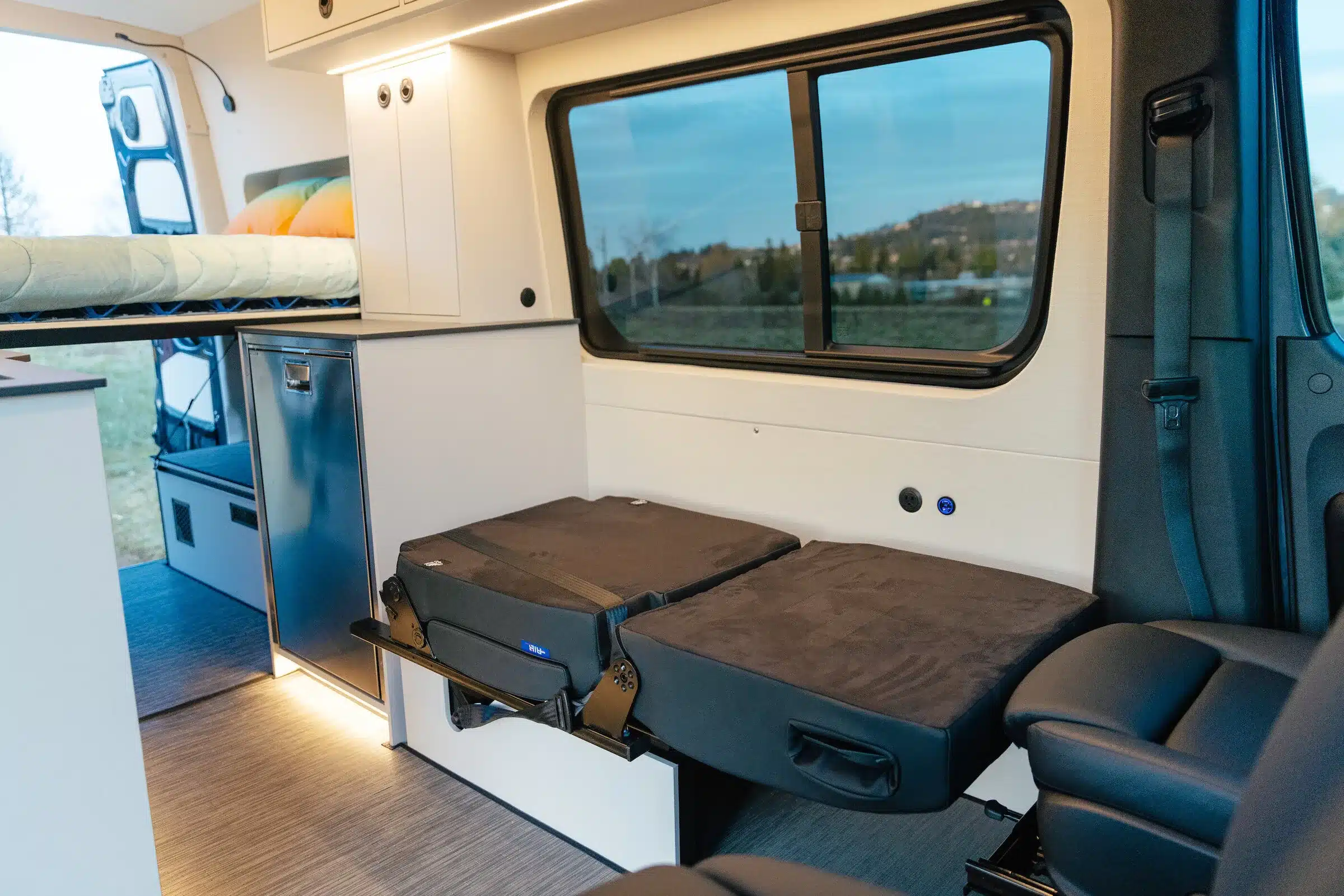 Innenansicht des Benchmark Apprentice Campervans mit Bett, Sitzbank und Stauraum