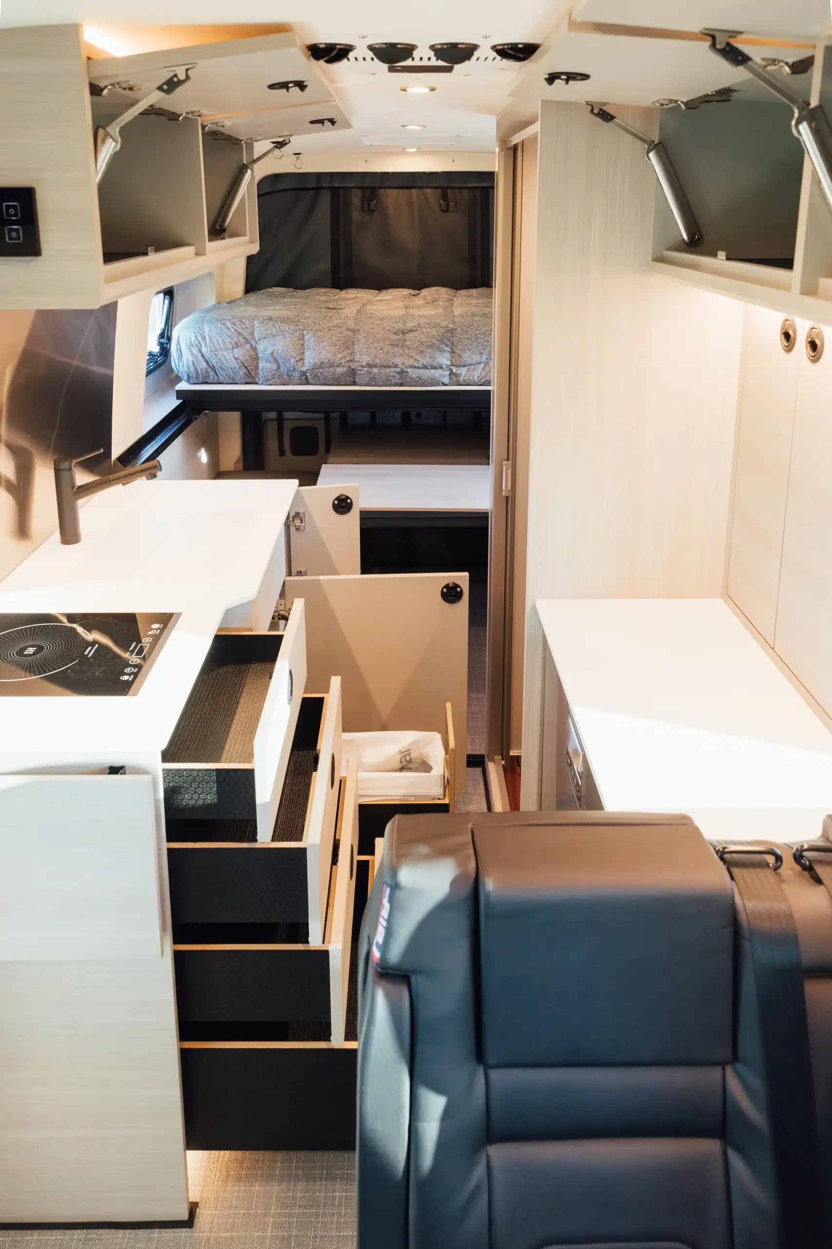 Innenansicht eines ausgebauten Mercedes Sprinter 170 4x4 mit moderner Küche, Stauraum und Bett im Heck