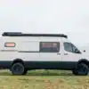 Seitenansicht eines Benchmark Breakaway Campervans auf Mercedes Sprinter 170 4x4 Basis mit Offroad-Bereifung und Dachaufbau, stehend auf einer Wiese