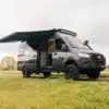 Benchmark Cosmos Sprinter 4x4 Reisemobil mit ausgefahrener Markise auf einer Wiese