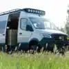 Benchmark CUBMOBILE 2024, ausgebauter Mercedes Sprinter 144 AWD mit Offroad-Komponenten und geöffnetem Seiteneingang auf einer Wiese