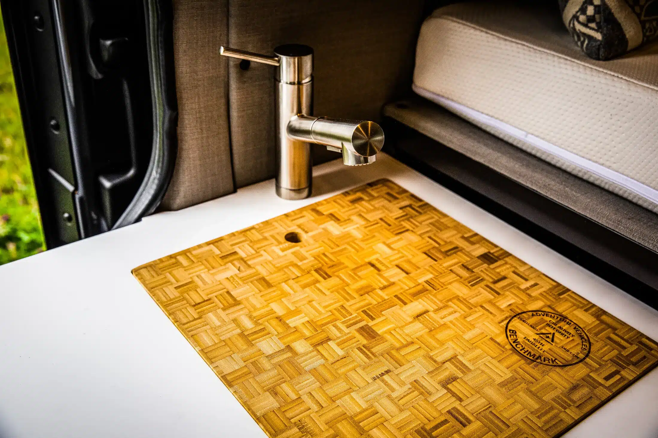 Detailansicht einer Küchenzeile mit Wasserhahn und Schneidebrett im Benchmark Elkat Campervan