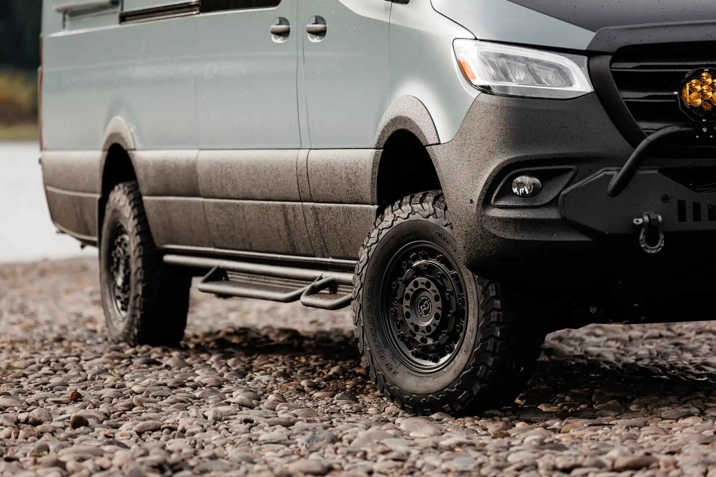 Vorderer Bereich eines Mercedes Sprinter 170 AWD mit Offroad-Reifen, Rhino-Felgen und Windenbumper auf steinigem Untergrund