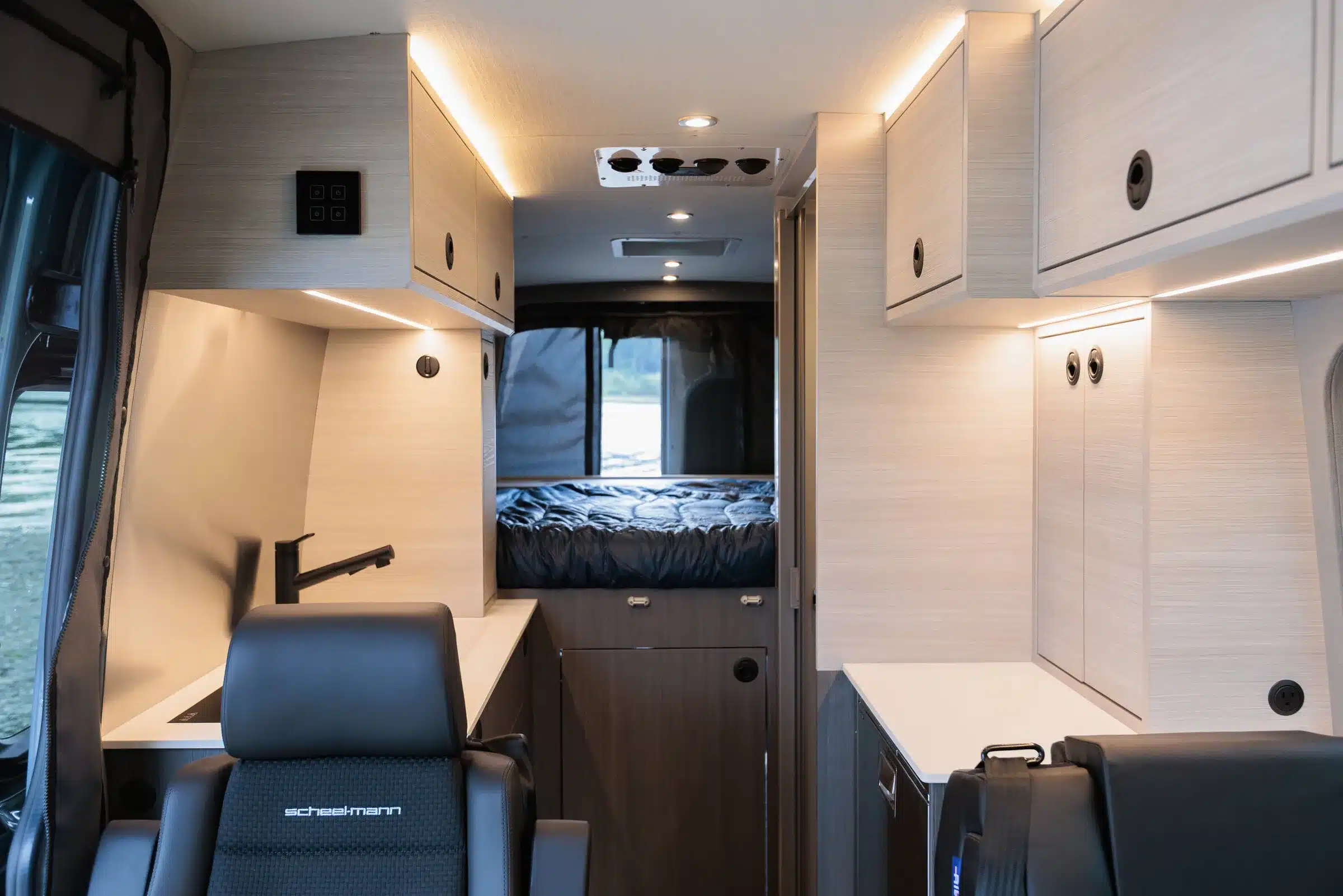 Hochwertig ausgebauter Innenraum eines Mercedes Sprinter 170 AWD mit Küchenzeile, Stauraum und Bett im Heck