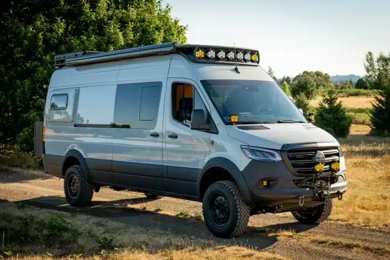 Benchmark LOATR Mercedes Sprinter 170 Allrad-Van mit Offroad-Umbau und Dachbeleuchtung auf einer Wiese