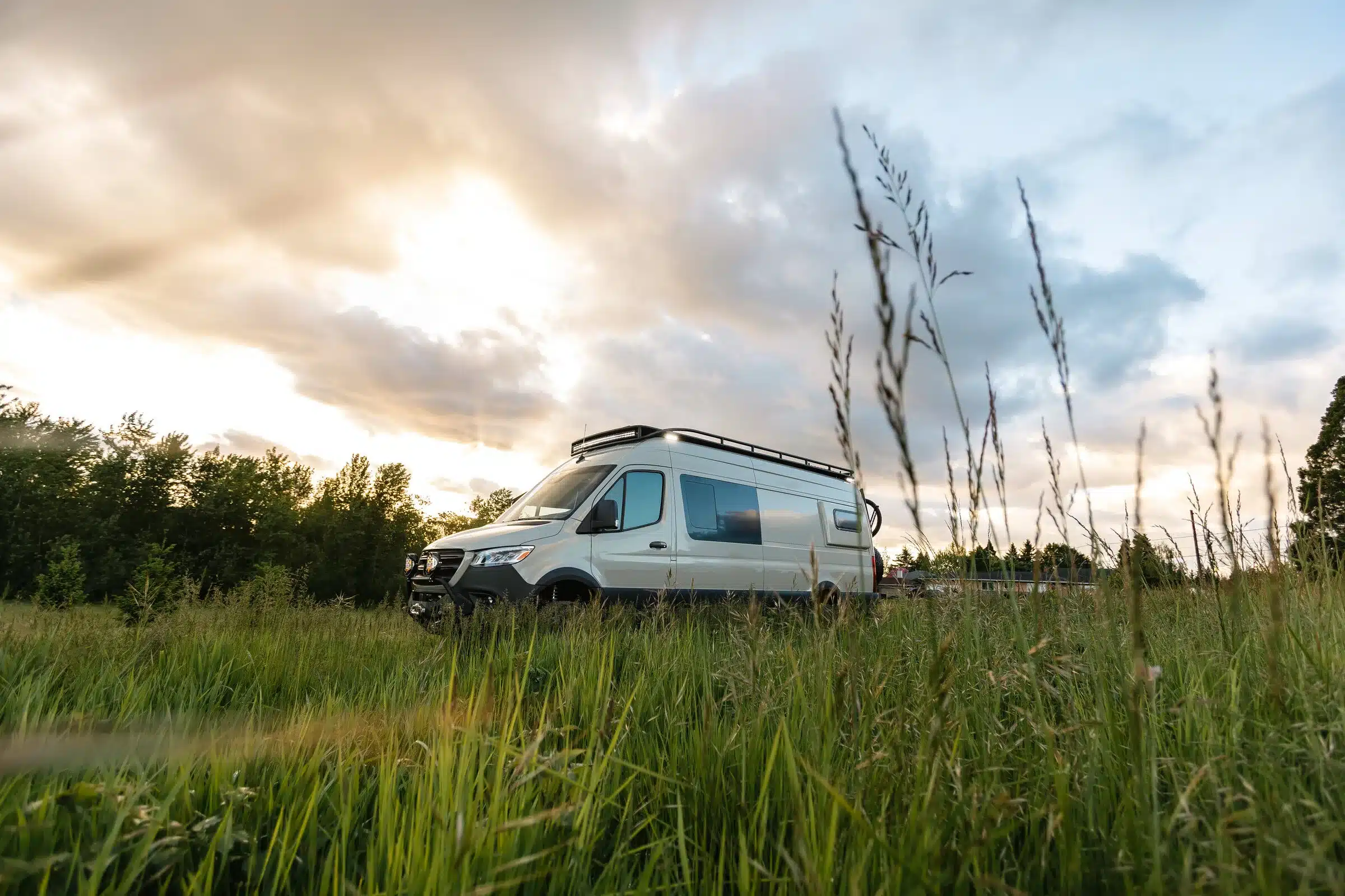 Mercedes Sprinter 170 4x4 Campervan steht auf einer Wiese bei Sonnenuntergang