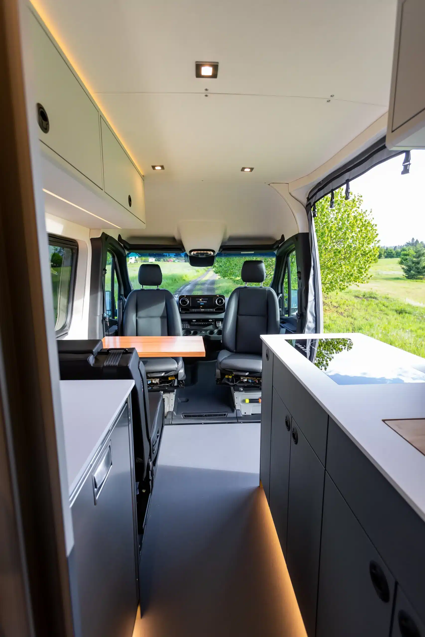 Blick in den Innenraum eines ausgebauten Mercedes Sprinter 170 4x4 mit moderner Küche, Sitzbereich und großem Fenster