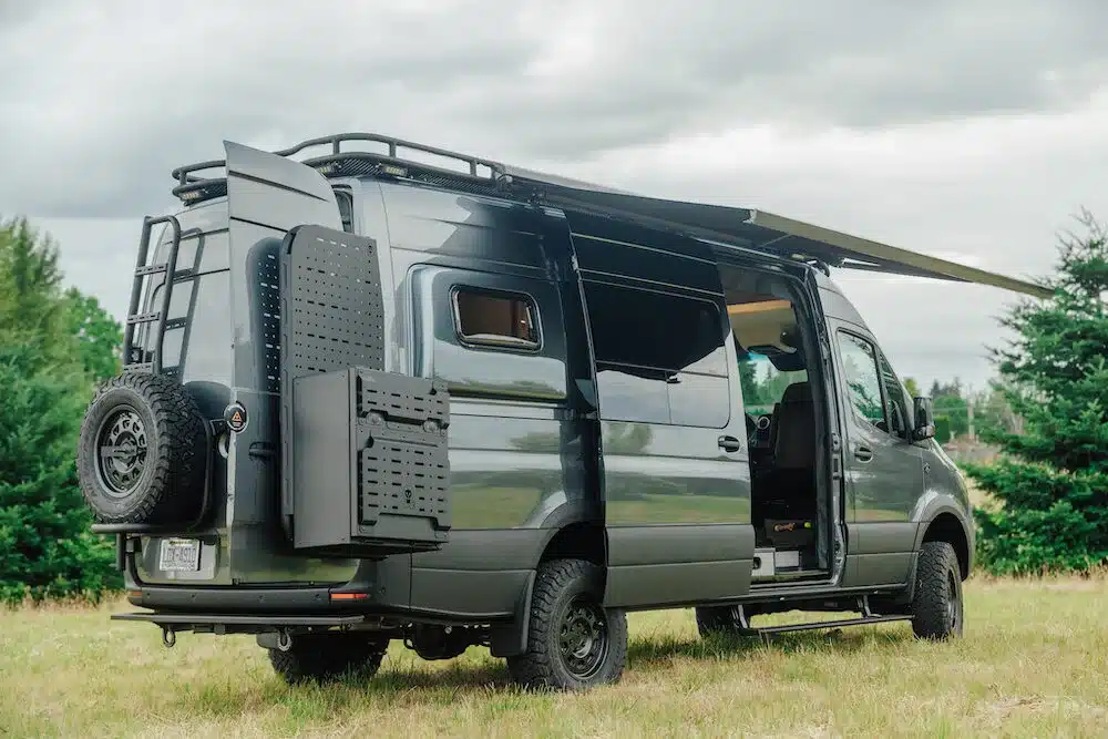 Benchmark Paradise Campervan auf Mercedes Sprinter 170 AWD Basis mit ausgeklapptem Sonnendach auf einer Wiese