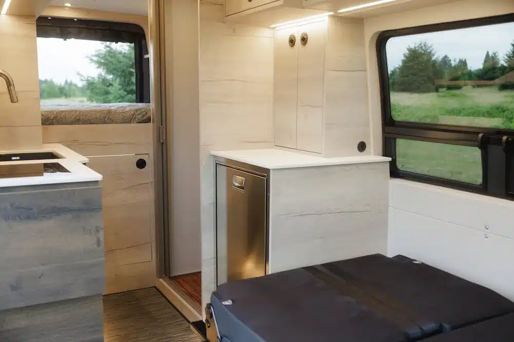 Hochwertig ausgebauter Innenraum eines Benchmark Paradise Campervans mit Küchenzeile, Stauraum und großem Fenster