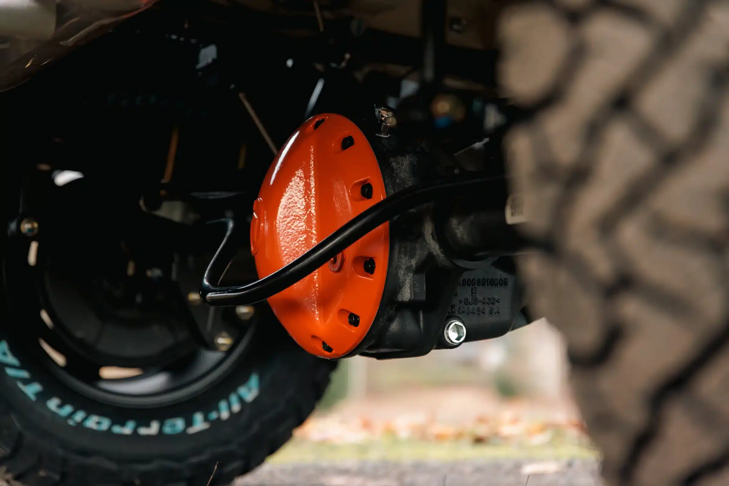 Nahaufnahme eines orangefarbenen Differentialschutzes und Offroad-Reifen am Benchmark Revive Sprinter
