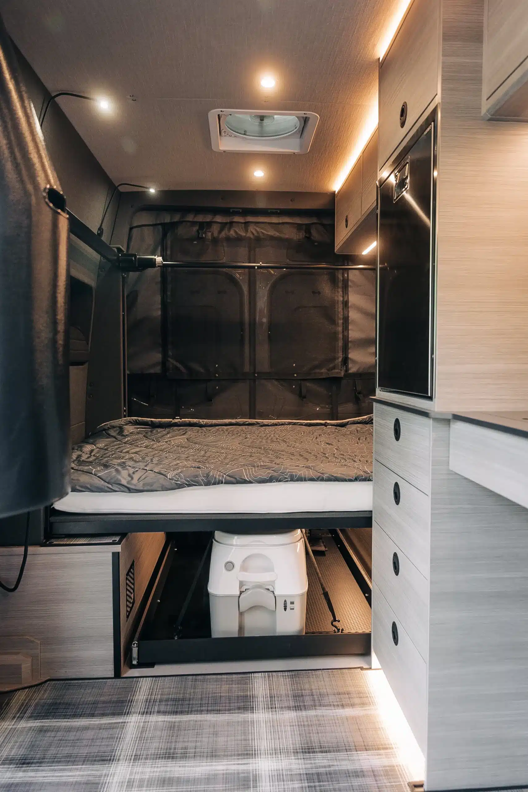 Innenansicht eines Benchmark Rule 76 Adventure Vans mit Bett, Stauraum und mobiler Toilette