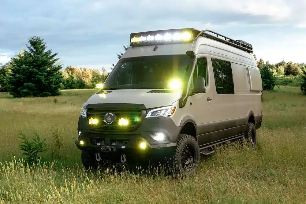 Benchmark Vehicles Cortland Campervan mit Offroad-Ausstattung und Zusatzbeleuchtung auf einer grünen Wiese