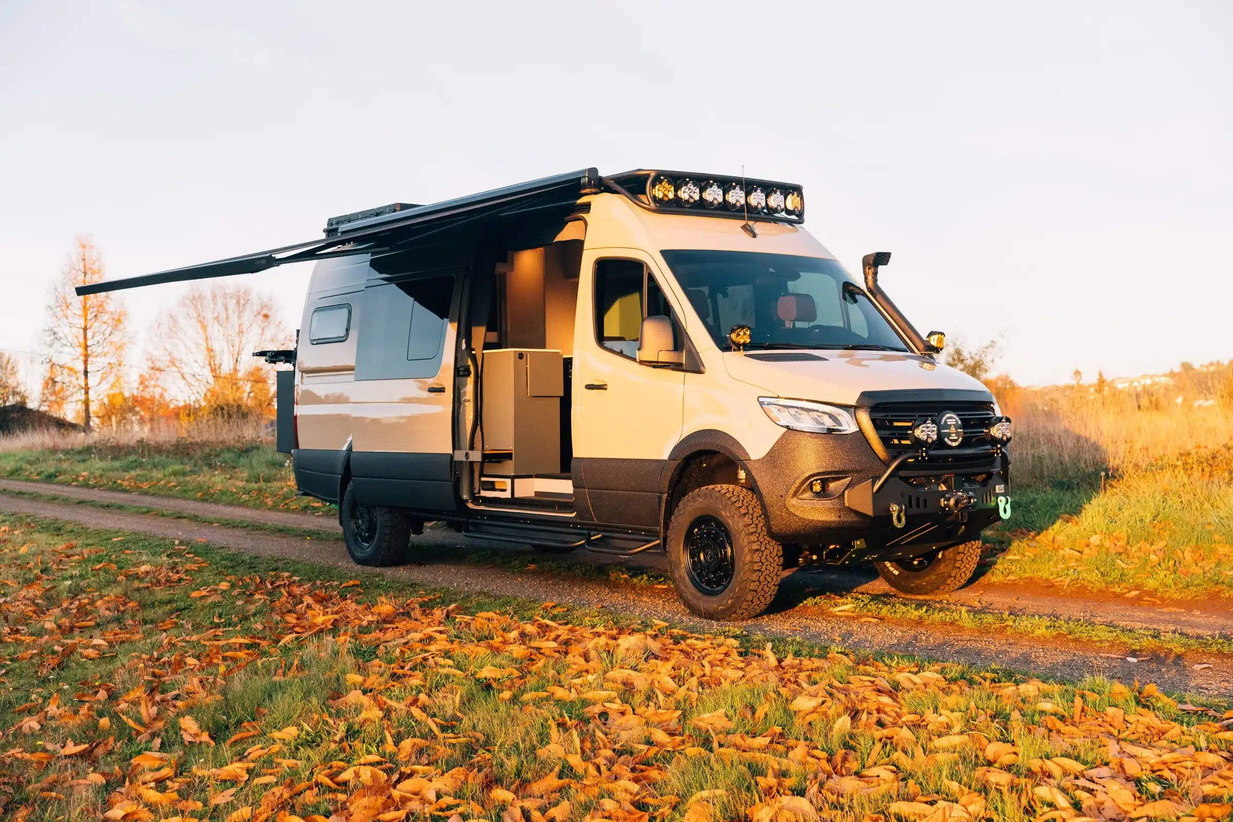 Benchmark Vehicles Green Lantern Campervan mit ausgefahrener Markise auf einem Feldweg