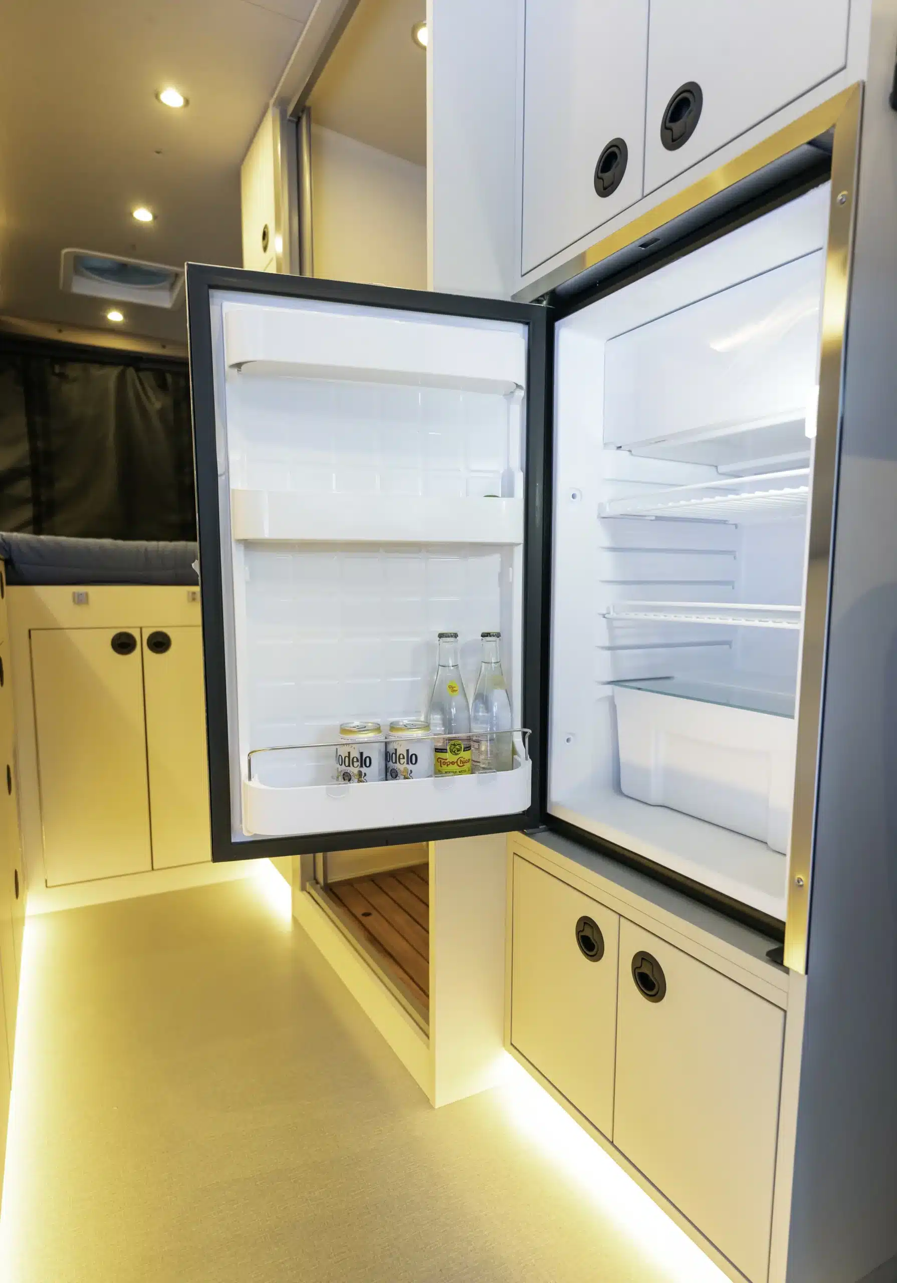 Geöffneter Vitrifrigo-Kühlschrank im Innenraum des ausgebauten Mercedes Sprinter Vans Lolo mit Getränken im Türfach