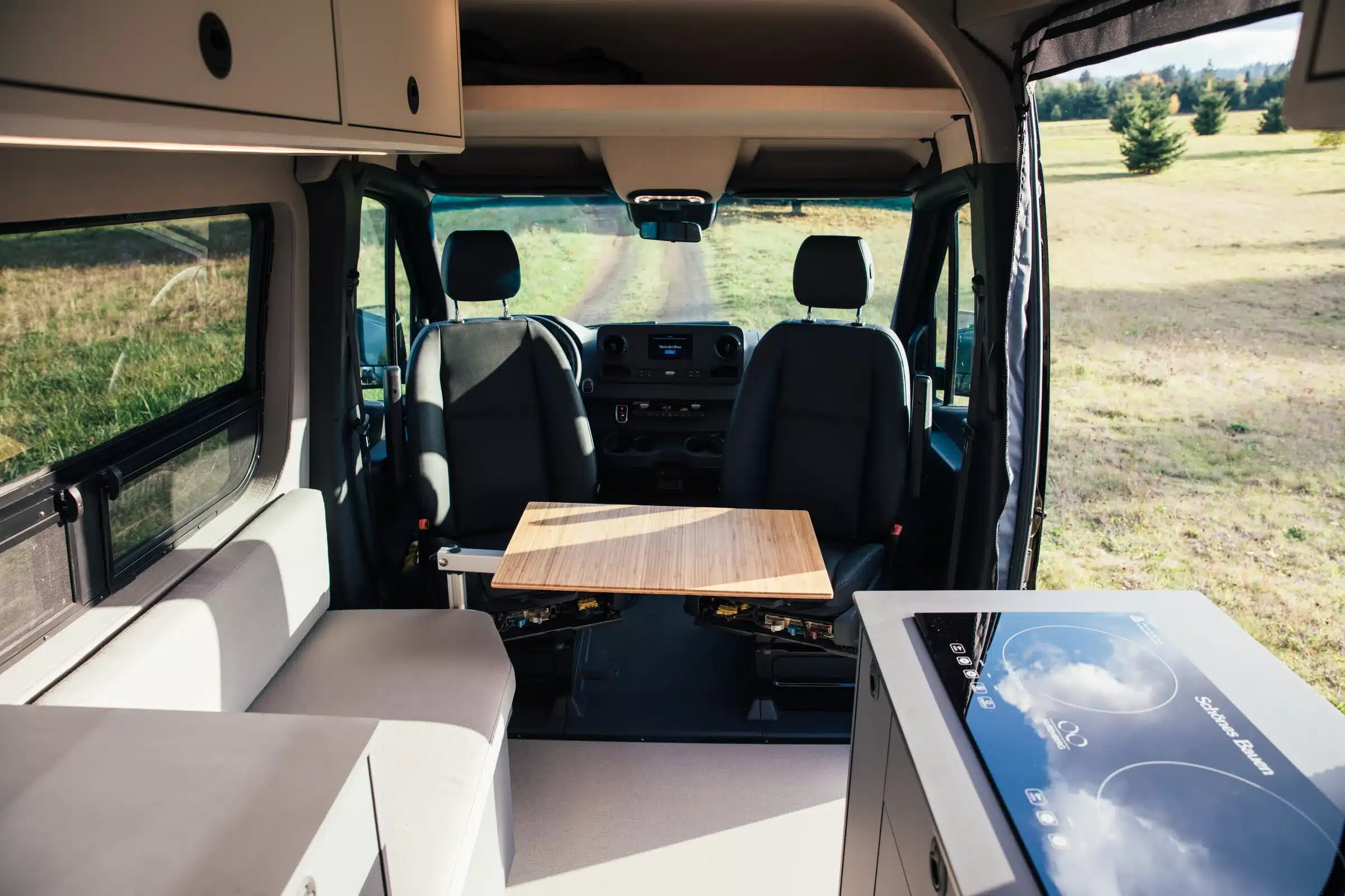 Blick in den Innenraum eines ausgebauten Mercedes Sprinter 170 4x4 Campervans mit Sitzgruppe, Tisch und Küchenzeile