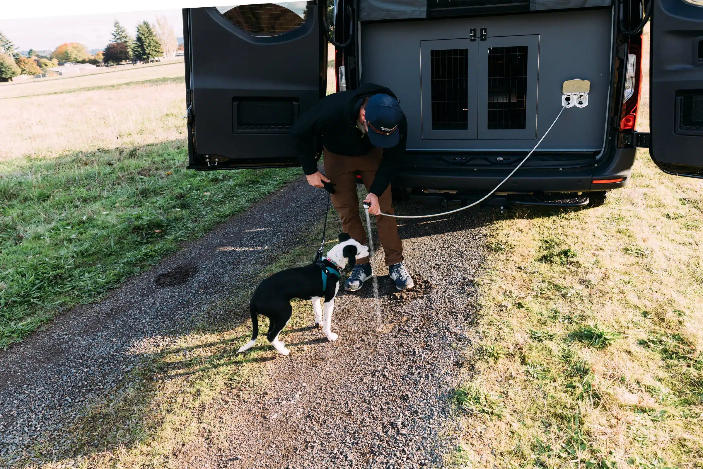 Person mit Hund am Heck eines ausgebauten Mercedes-Benz Sprinter Campervans mit integrierter Hundebox und Outdoor-Ausstattung