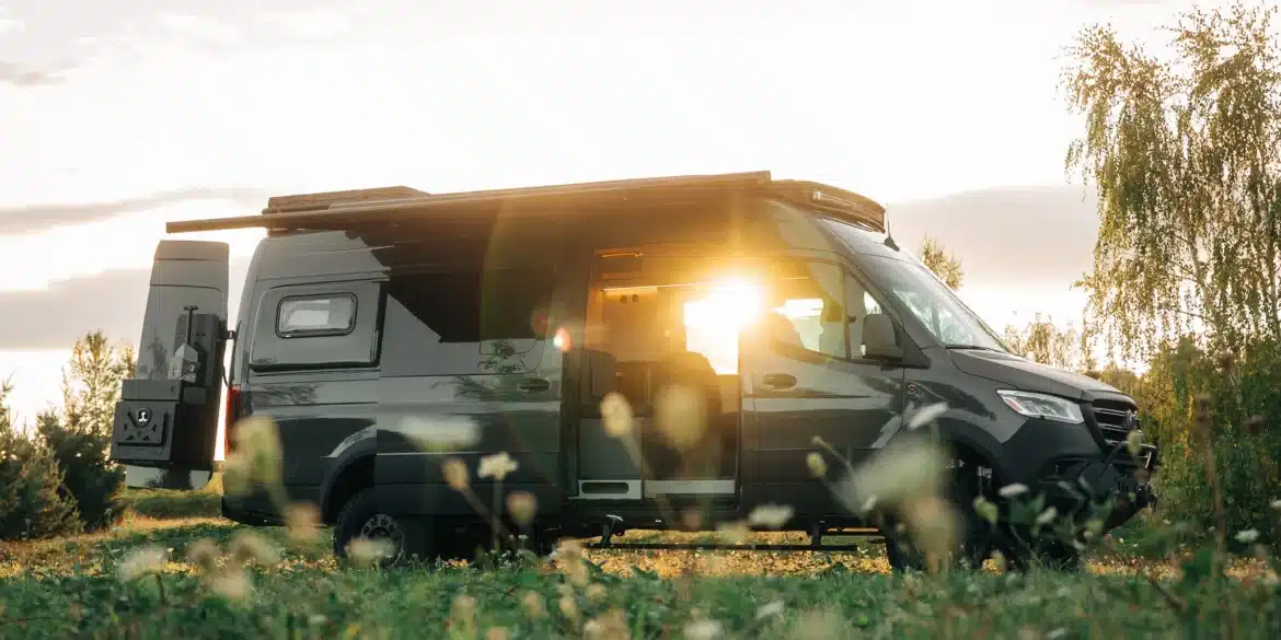 Benchmark Vehicles Salathé Kastenwagen steht auf einer Wiese im Sonnenuntergang mit geöffneter Tür
