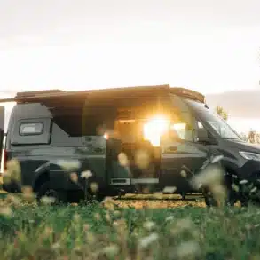 Benchmark Vehicles Salathé Kastenwagen steht auf einer Wiese im Sonnenuntergang mit geöffneter Tür
