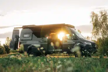 Benchmark Vehicles Salathé Kastenwagen steht auf einer Wiese im Sonnenuntergang mit geöffneter Tür