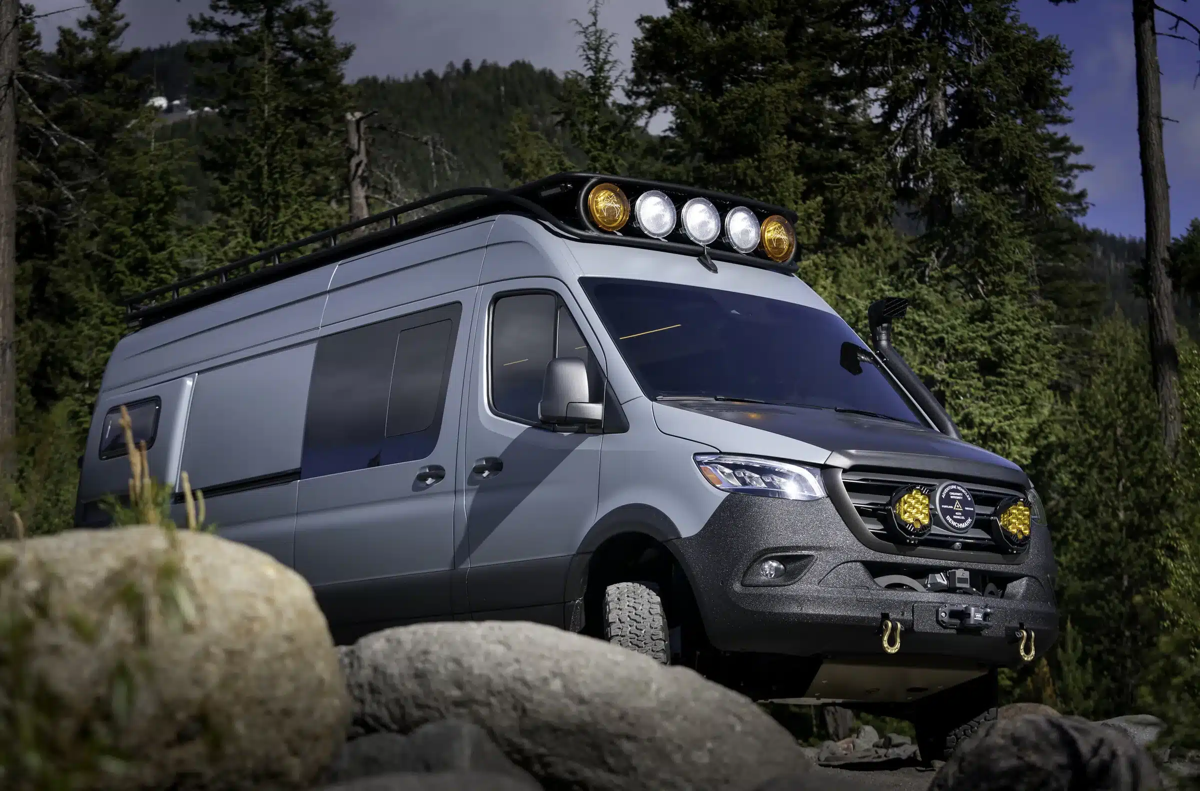 Benchmark Vehicles SIBO Campervan auf Mercedes Sprinter 170 4x4, ausgestattet mit Offroad-Zubehör, Dachscheinwerfern und Schnorchel, im Waldgelände
