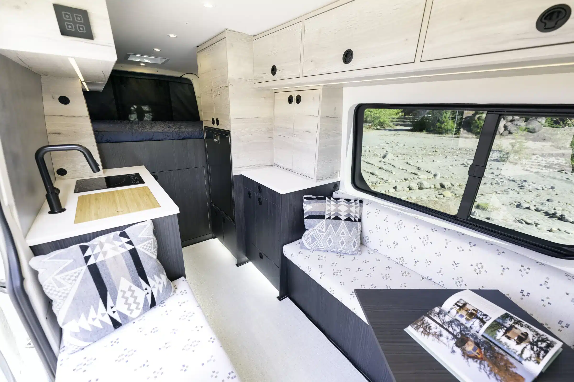 Hochwertig ausgebauter Innenraum eines Benchmark Vehicles SIBO Mercedes Sprinter Campervans mit Küche, Sitzbereich und Bett.