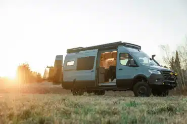 Benchmark Vehicles Strider Offroad-Campervan mit geöffneter Tür auf einer Wiese im Sonnenuntergang