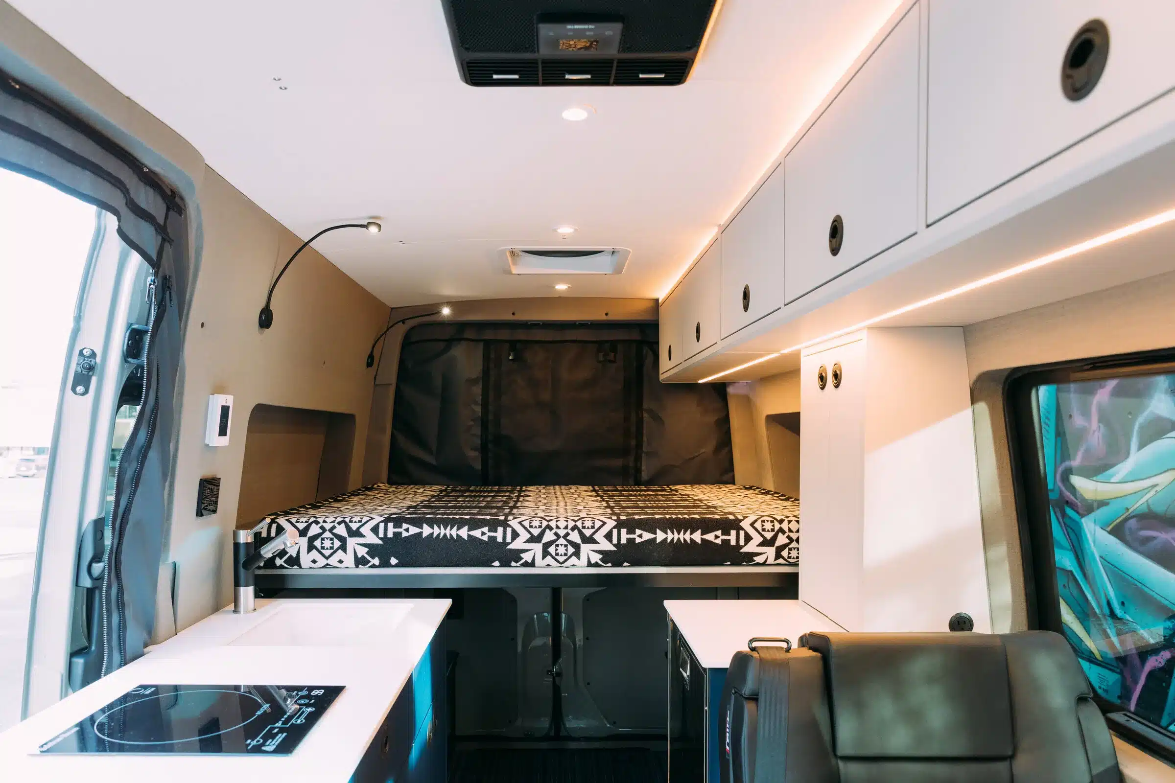 Innenansicht eines Benchmark Zodiac Vans mit Bett, Stauraum, Küchenzeile und Sitzgelegenheit