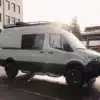 Benchmark Zodiac Expeditionsvan mit Offroad-Ausstattung auf einem Parkplatz vor einem modernen Gebäude