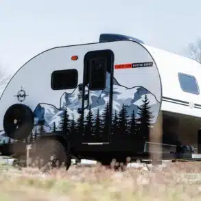 Seitenansicht des Big Buggy 14 Offroad-Campers mit Berg- und Waldmotiv, abgestellt in der Natur