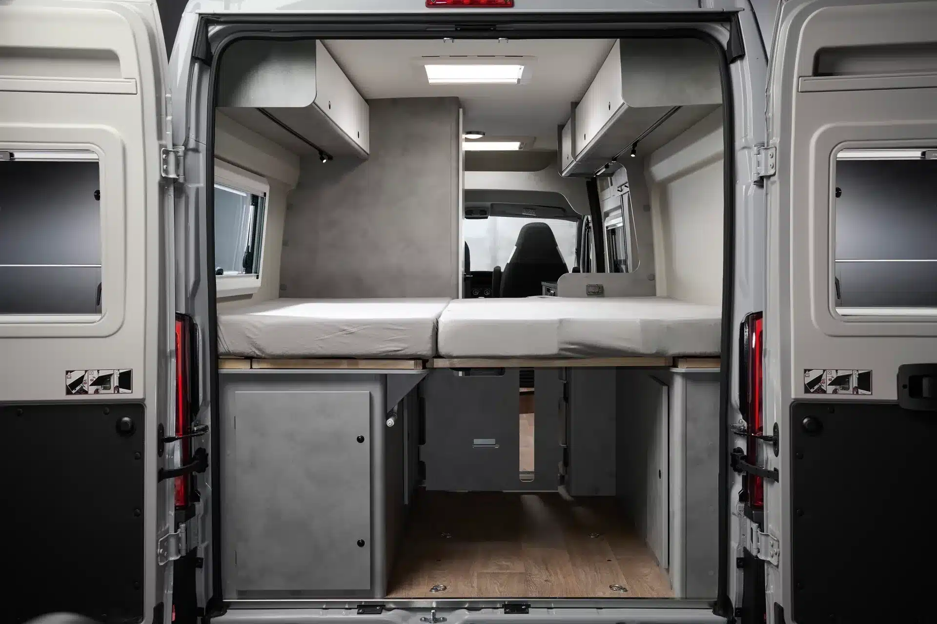 Innenansicht des CROSSCAMP ADVTR 6.4 EF von hinten mit zwei Längsbetten und viel Stauraum unter den Betten