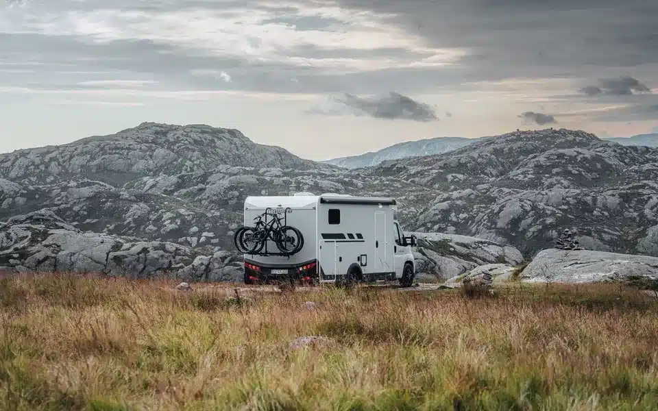 Crosscamp EXPDN 7.4 E Wohnmobil mit Fahrrädern am Heck in einer bergigen Landschaft