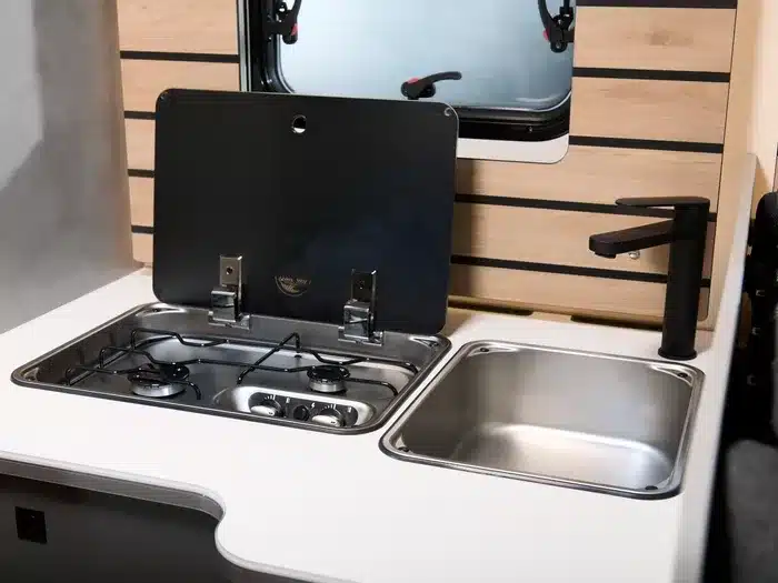 Kompakte Küchenzeile mit Gasherd, Spüle und Wasserhahn im Crosscamp EXPDN 7.4 E Wohnmobil