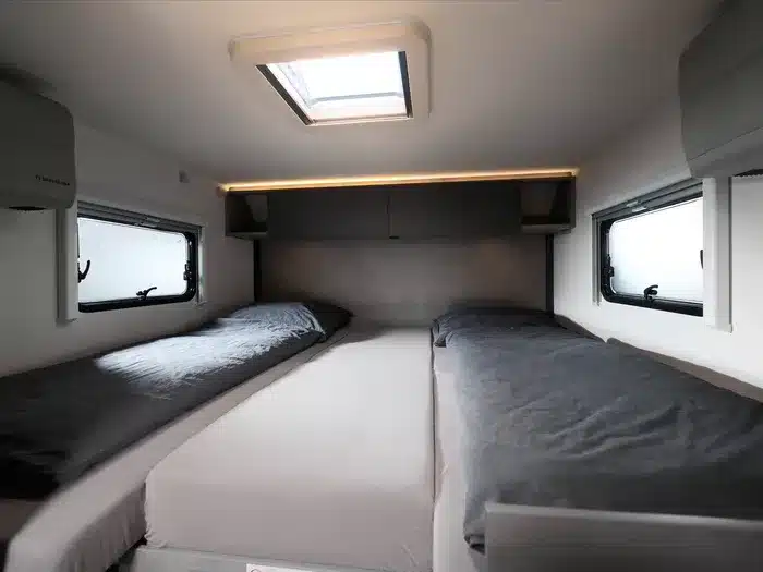 Innenansicht des Schlafbereichs mit zwei längs angeordneten Einzelbetten im Crosscamp EXPDN 7.4 E Wohnmobil