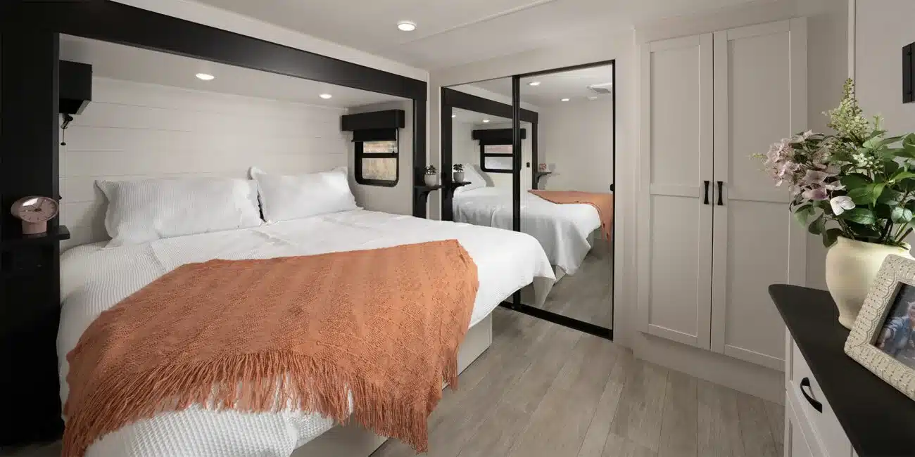 Innenansicht eines Schlafzimmers mit großem Bett, Spiegelschrank und moderner Einrichtung im Cyclone Fifth Wheel Toy Hauler