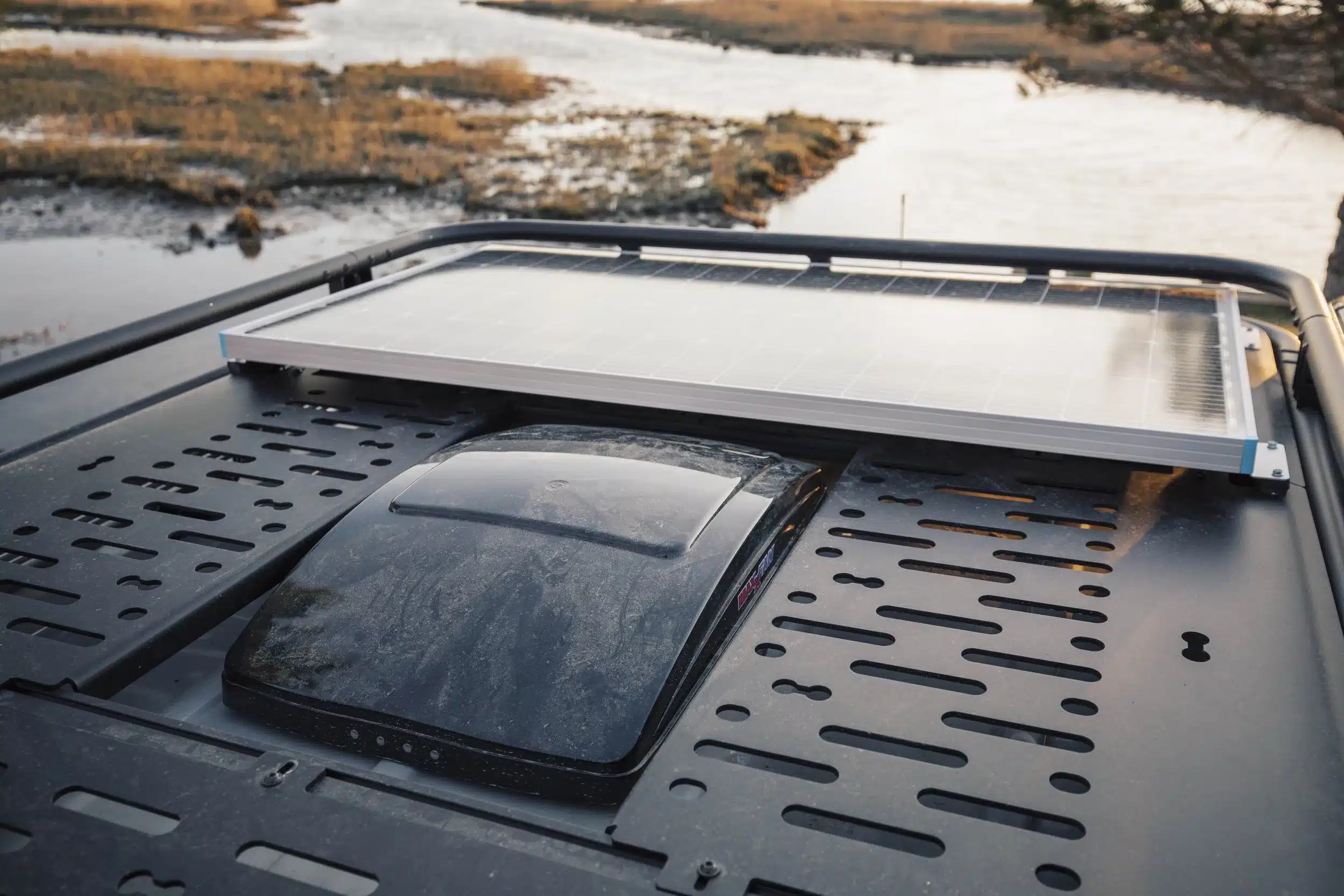 Solarmodul und Dachlüfter auf dem Dach eines Campervans mit Blick auf eine Flusslandschaft