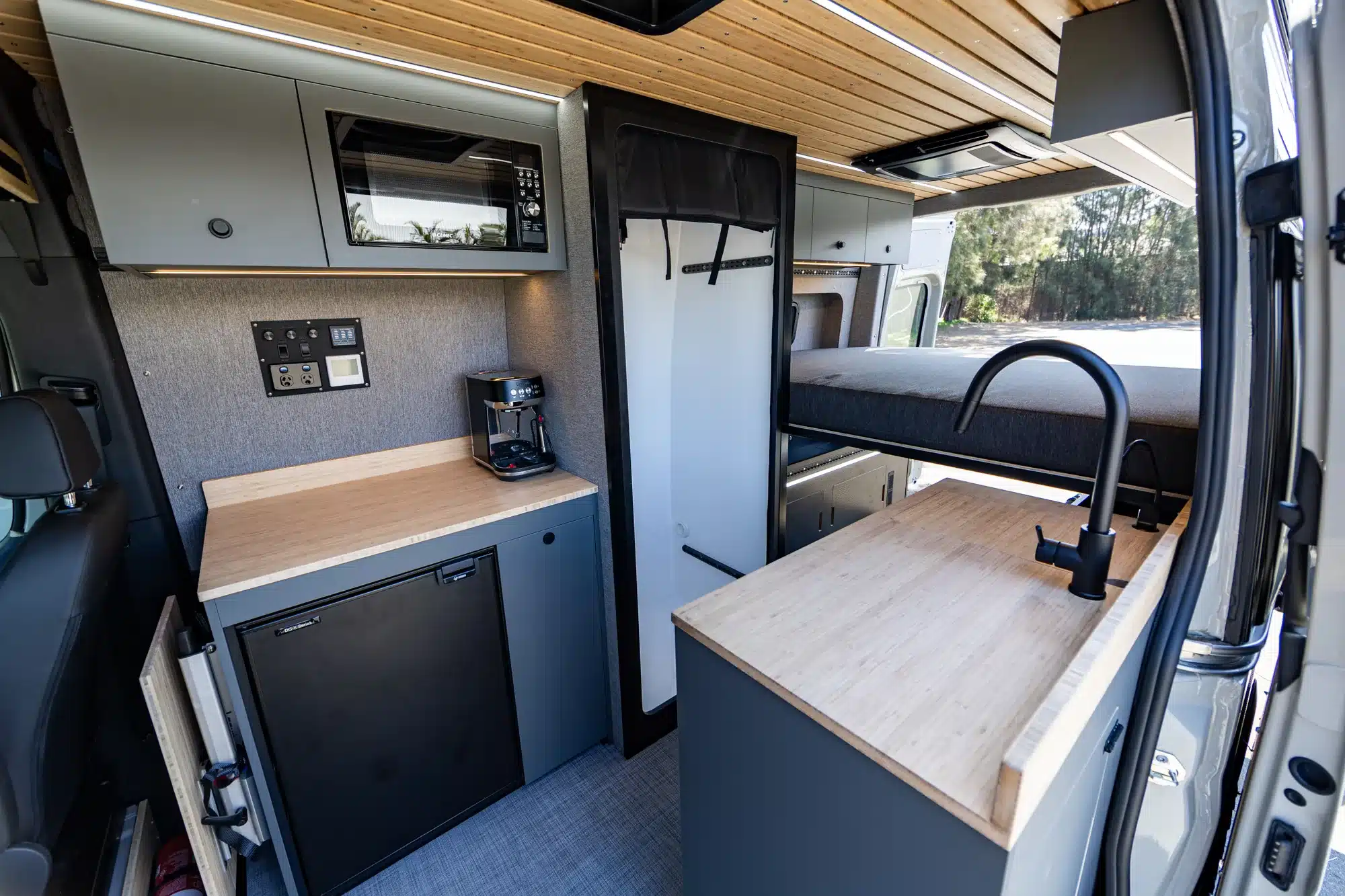 Innenansicht eines Summit M1 Vans mit Küchenzeile, Stauraum, Schlafbereich und modernen Materialien