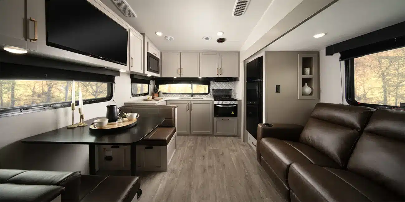 Innenansicht eines Sundance Fifth Wheel Wohnwagens mit moderner Küche, Essbereich und Ledersofa